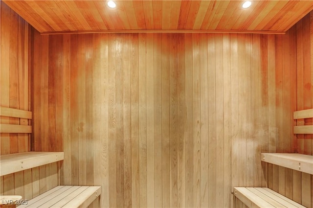 sauna with wood walls, wooden ceiling, and recessed lighting