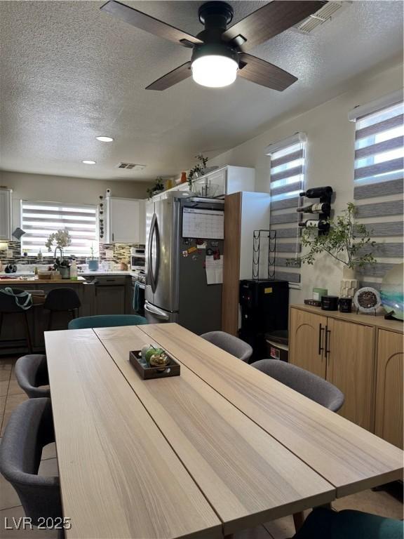 dining room with a textured ceiling, plenty of natural light, ceiling fan, and light tile patterned flooring