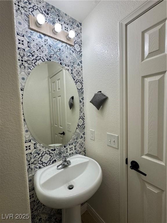 bathroom with a sink and wallpapered walls