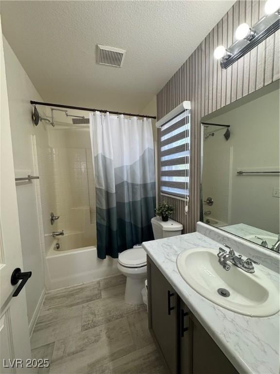 bathroom featuring shower / bath combo with shower curtain, vanity, toilet, a textured ceiling, and baseboards
