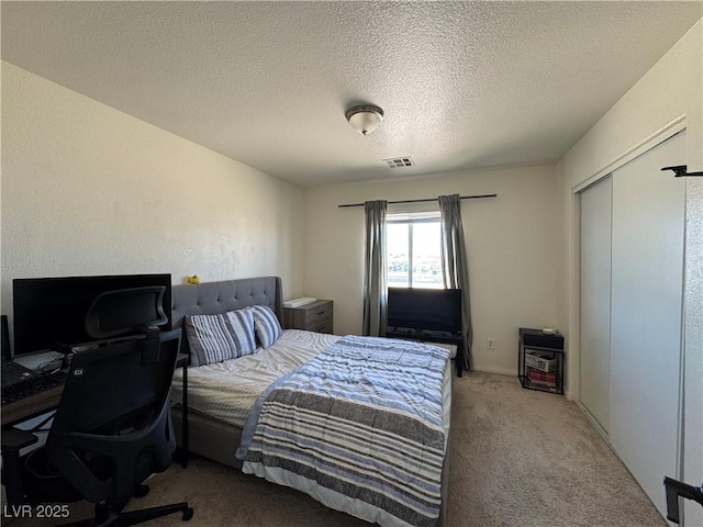 carpeted bedroom featuring a desk, a textured ceiling, and a closet