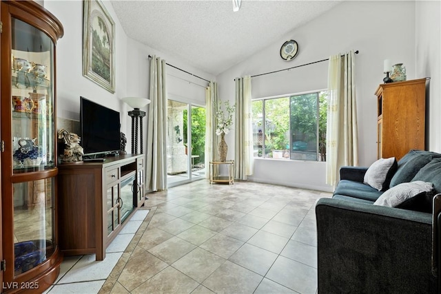 living room featuring lofted ceiling, healthy amount of natural light, a textured ceiling, and light tile patterned floors