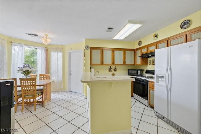 kitchen with white fridge with ice dispenser, gas range, under cabinet range hood, light countertops, and light tile patterned floors
