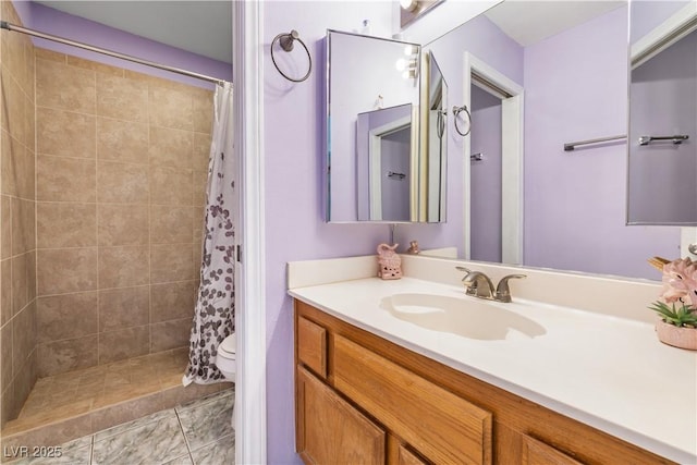 bathroom with toilet, tiled shower, and vanity