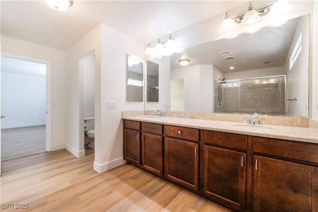 6821 Treble Clef Ave, Las Vegas, NV 89139 - bathroom featuring wood finished floors, a stall shower, toilet, double vanity, and baseboards