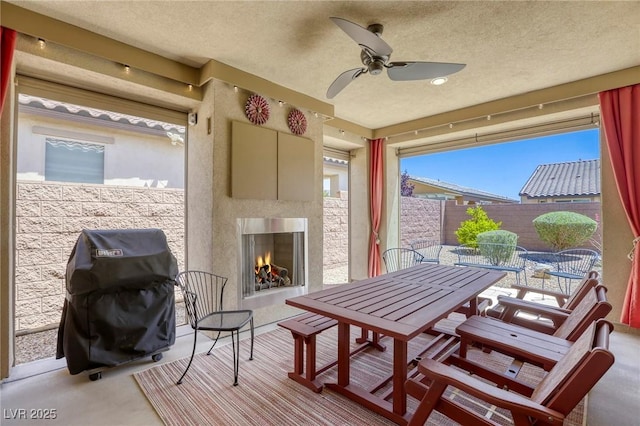 5650 Pleasant Palms St, North Las Vegas, NV 89081 - view of patio / terrace with a warm lit fireplace, outdoor dining area, a fenced backyard, a grill, and a ceiling fan