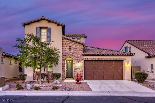 5650 Pleasant Palms St, North Las Vegas, NV 89081 - mediterranean / spanish-style house with a tile roof, an attached garage, driveway, stucco siding, and brick siding