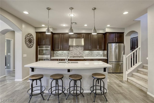5650 Pleasant Palms St, North Las Vegas, NV 89081 - kitchen with appliances with stainless steel finishes, under cabinet range hood, a sink, arched walkways, and recessed lighting