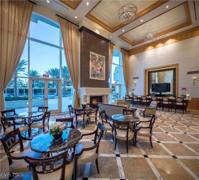 2777 Paradise Rd Unit 2701Ph, Las Vegas, NV 89109 - dining space featuring a towering ceiling, a lit fireplace, inlaid floor details, wood walls, and ornamental molding