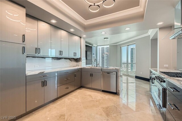 2777 Paradise Rd Unit 2701Ph, Las Vegas, NV 89109 - kitchen with stainless steel appliances, a tray ceiling, ornamental molding, a peninsula, and gray cabinets