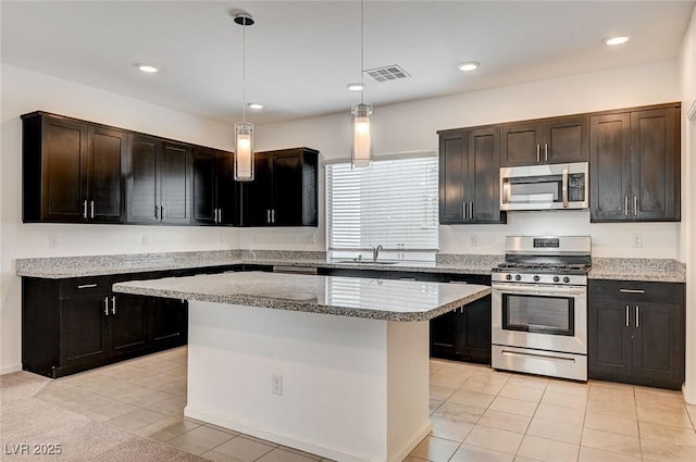 8056 Haywood Estate Ave, Las Vegas, NV 89113 - kitchen featuring stainless steel appliances, light tile patterned floors, hanging light fixtures, light stone countertops, and a kitchen island