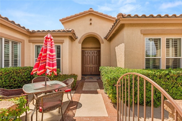 215 Great Gable Dr, Las Vegas, NV 89183 - entrance to property with stucco siding, outdoor dining space, a patio area, and a tiled roof