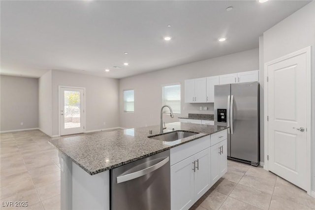 kitchen featuring stainless steel appliances, a sink, stone counters, white cabinets, and light tile patterned flooring