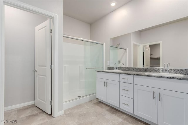 bathroom with a stall shower, double vanity, recessed lighting, and baseboards