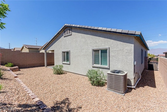 view of property exterior with cooling unit, stucco siding, and a fenced backyard
