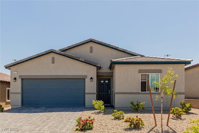view of front facade featuring a garage, decorative driveway, stucco siding, and a tiled roof