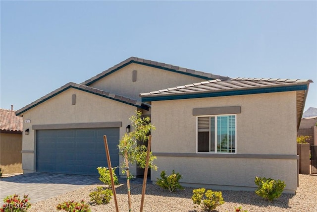 view of front facade featuring an attached garage, decorative driveway, stucco siding, and a tiled roof