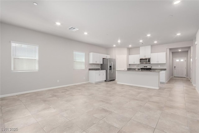kitchen featuring stainless steel appliances, open floor plan, a sink, white cabinets, and recessed lighting