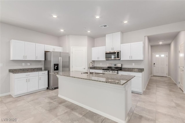 10257 Sequoia Falls Pl, Las Vegas, NV 89149 - kitchen featuring a sink, stainless steel appliances, a kitchen island with sink, dark stone countertops, and white cabinetry