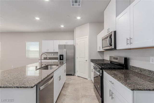 kitchen with appliances with stainless steel finishes, a sink, recessed lighting, white cabinetry, and dark stone countertops