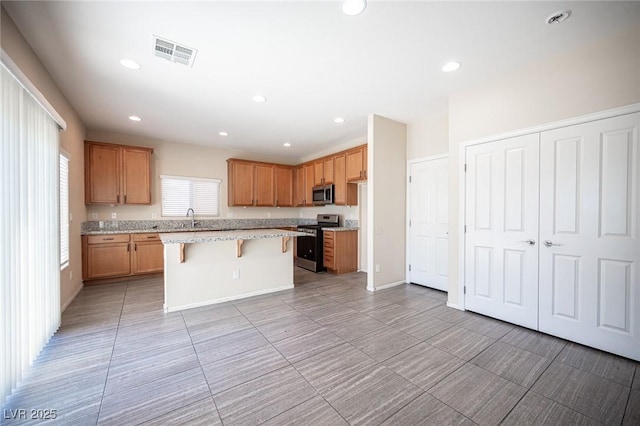 1405 Gilbert Creek Ave, North Las Vegas, NV 89031 - kitchen with stainless steel appliances, a kitchen breakfast bar, a sink, a center island, and light stone countertops