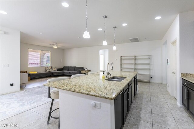 kitchen with a sink, light tile patterned floors, a kitchen breakfast bar, hanging light fixtures, and recessed lighting