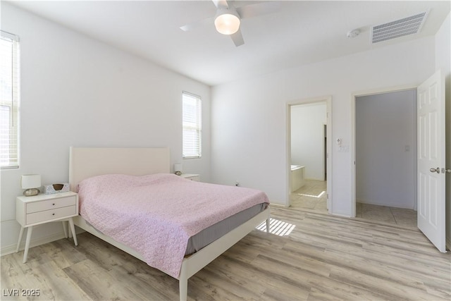 bedroom with light wood-style floors, a ceiling fan, connected bathroom, and baseboards