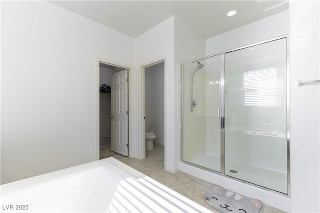full bathroom featuring a shower stall, tile patterned floors, toilet, and a spacious closet