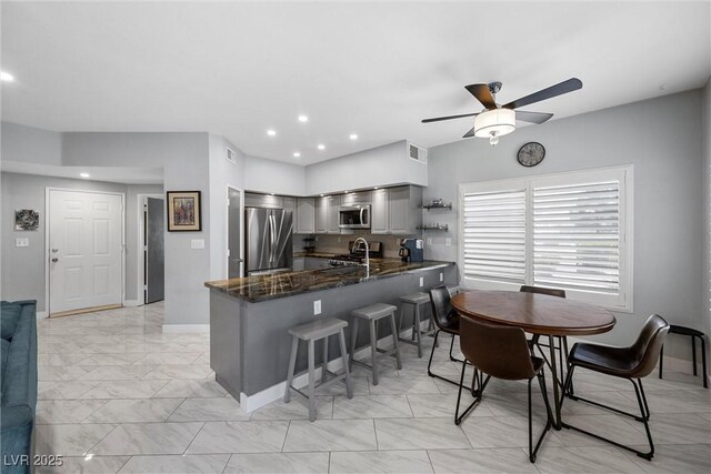 4821 Black Bear Rd Unit 101, Las Vegas, NV 89149 - kitchen with appliances with stainless steel finishes, a peninsula, a ceiling fan, light marble finish flooring, and a kitchen breakfast bar