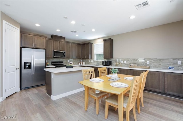 8873 Howell St, Las Vegas, NV 89166 - kitchen with appliances with stainless steel finishes, dark brown cabinetry, light countertops, tasteful backsplash, and light wood-style floors