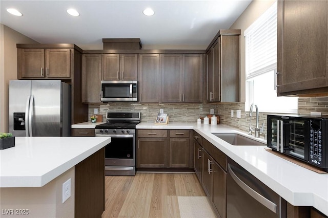 8873 Howell St, Las Vegas, NV 89166 - kitchen with appliances with stainless steel finishes, a sink, light wood-type flooring, light countertops, and recessed lighting