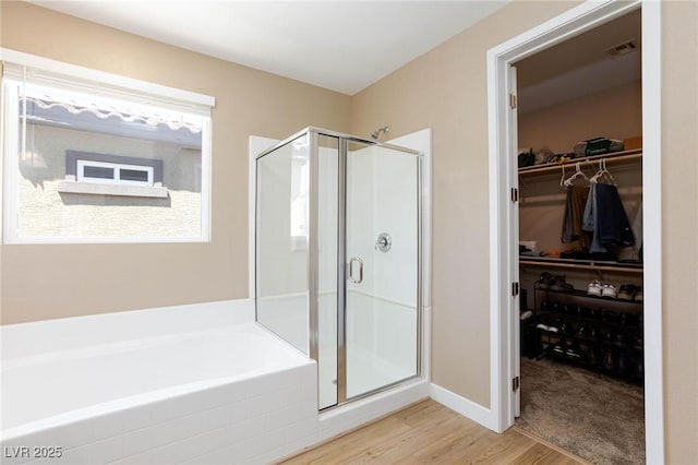 8873 Howell St, Las Vegas, NV 89166 - bathroom featuring a stall shower, wood finished floors, a walk in closet, and a garden tub