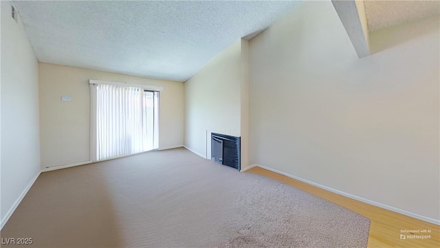 unfurnished living room featuring a fireplace, baseboards, a textured ceiling, and heating unit