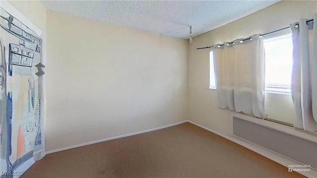 empty room featuring a textured ceiling, carpet floors, and baseboards
