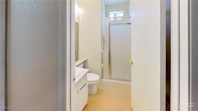 full bathroom featuring vanity, toilet, a shower stall, and wood finished floors