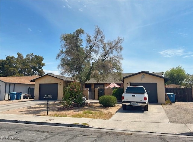 ranch-style home with driveway, an attached garage, stucco siding, and fence