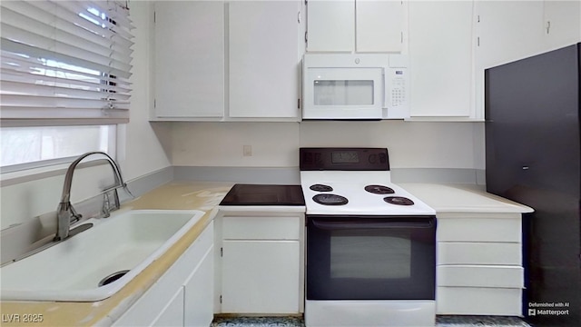 kitchen featuring range with electric stovetop, white microwave, a sink, white cabinetry, and light countertops