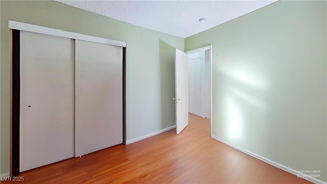 unfurnished bedroom with wood finished floors, a closet, and baseboards