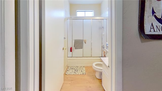 full bathroom featuring wood finished floors, toilet, combined bath / shower with glass door, and vanity