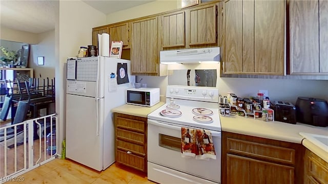 kitchen with white appliances, ventilation hood, light countertops, and brown cabinets
