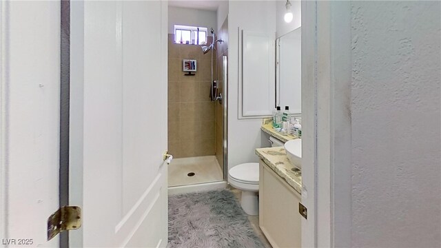 full bath featuring vanity, a stall shower, toilet, and a textured wall