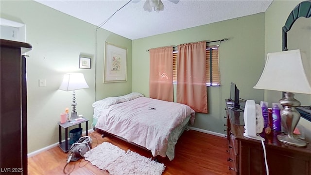 bedroom featuring wood finished floors, baseboards, and a textured ceiling