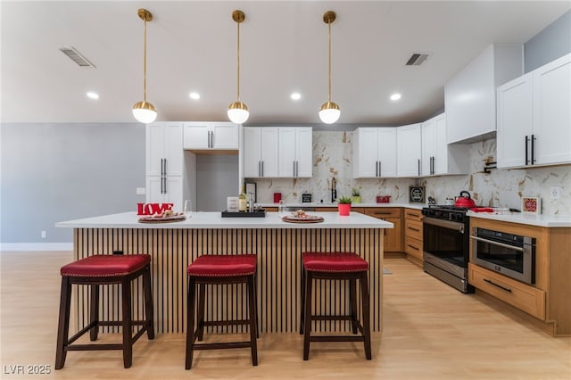 kitchen featuring stainless steel appliances, light wood-style floors, decorative backsplash, a breakfast bar area, and recessed lighting