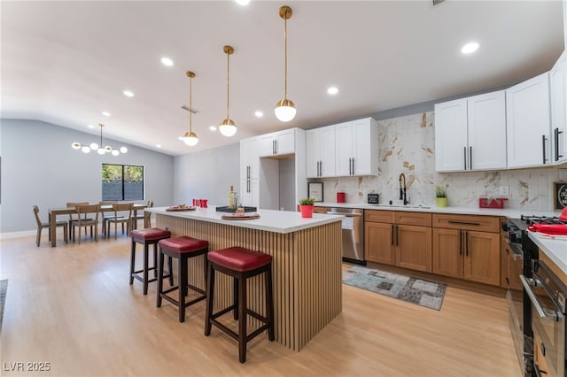 kitchen with stainless steel appliances, a sink, backsplash, light wood-style flooring, and recessed lighting
