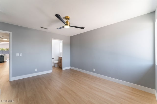 unfurnished bedroom featuring light wood-style flooring, baseboards, ensuite bath, and a ceiling fan