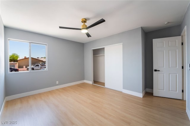 unfurnished bedroom featuring light wood-style flooring, a closet, baseboards, and a ceiling fan
