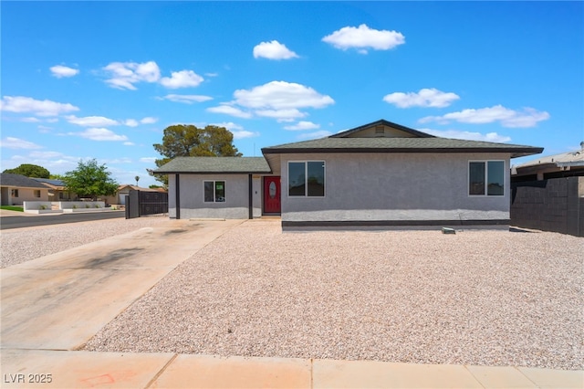 single story home with stucco siding, concrete driveway, and fence