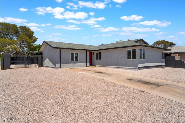 ranch-style home featuring fence, stucco siding, a gate, and driveway