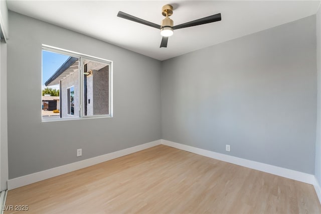 empty room with wood finished floors, a ceiling fan, and baseboards