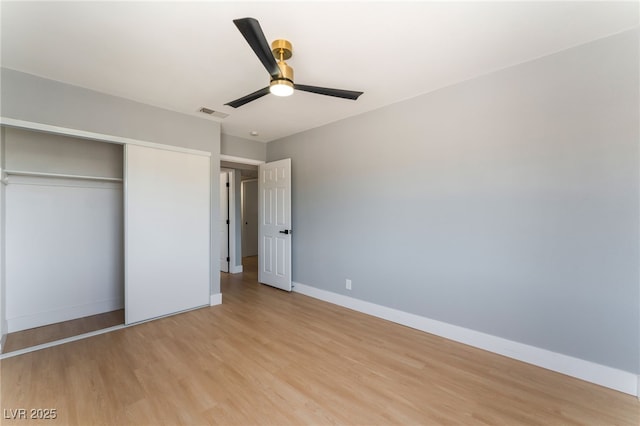 unfurnished bedroom featuring light wood finished floors, baseboards, and a closet